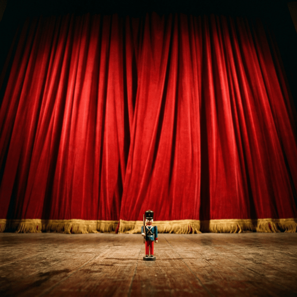 Toy soldier figurine standing on wooden stage floor with red theater curtains in background